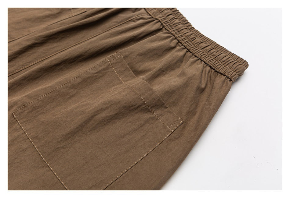 Close-up of a large patch pocket and elastic waistband on brown trousers.