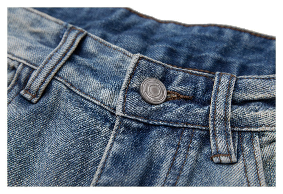 Close-up of the blue washed jeans' waistband, belt loops, and metal button.