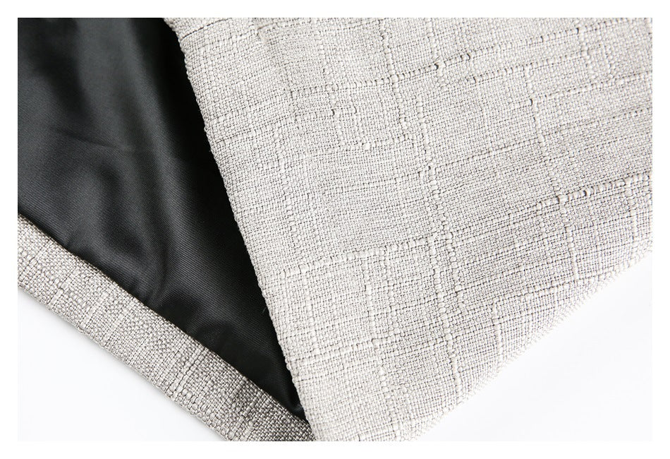 Close-up of light beige textured garment fabric beside a black lining and folded edge.
