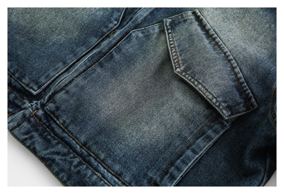 Close-up of a faded blue denim jacket pocket flap, seams, and contrasting tan stitching.