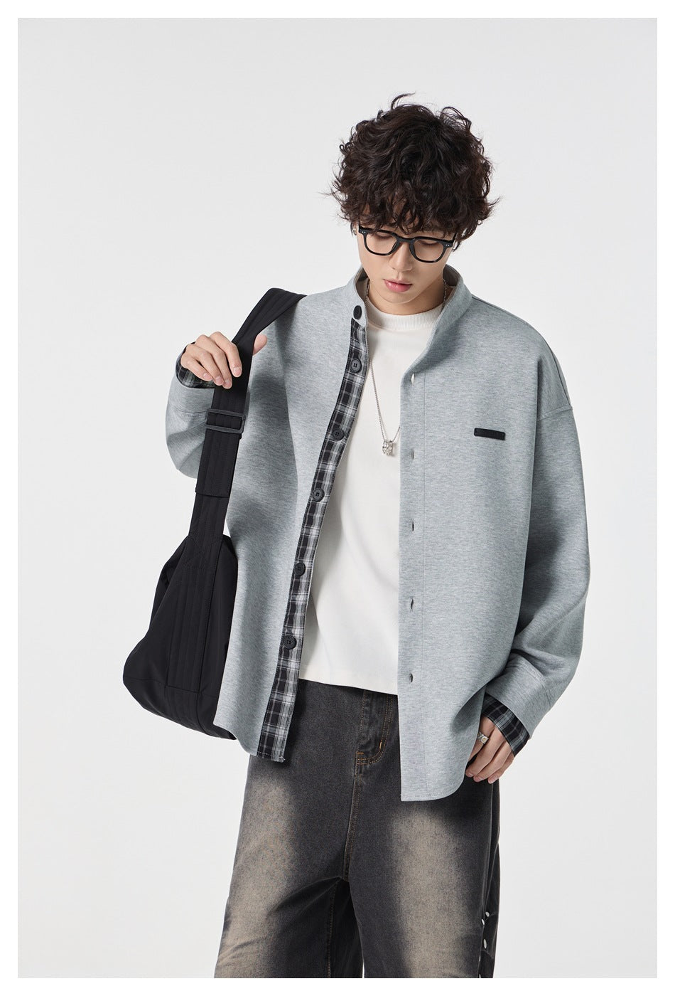 Model wearing an open light gray stand-collar jacket with plaid placket and cuffs over a white top.