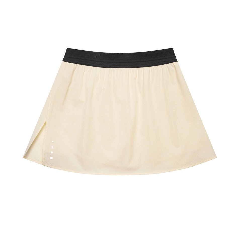 Beige A-line mini skirt with black elastic waistband, side slit and small graduated dots near the hem