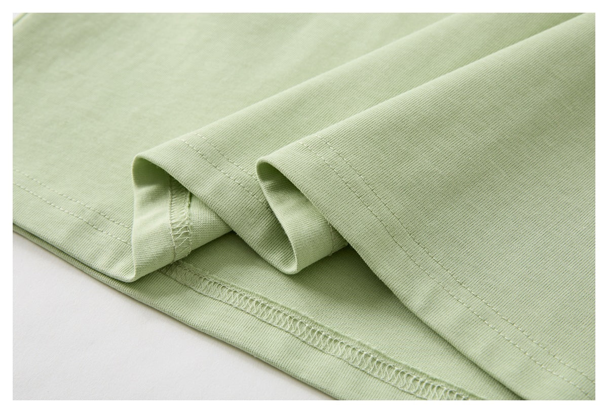 Close-up showing stitching and overlocked seams on pale green garment fabric.