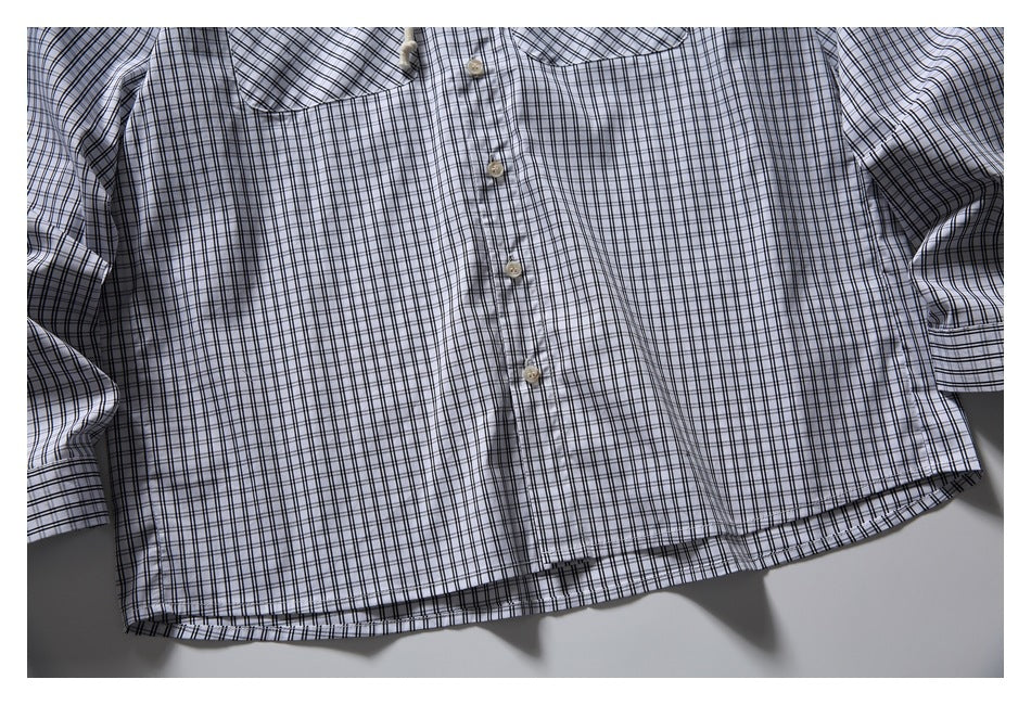 Flat-lay front of a light shirt with a black plaid grid, button front, collar, and long sleeves.