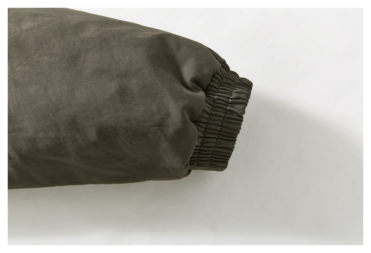Close-up of a dark olive jacket sleeve ending in a gathered elastic cuff.