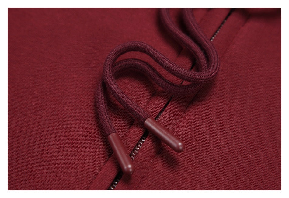 Close-up of burgundy hoodie drawstrings with molded tips beside the front zipper.