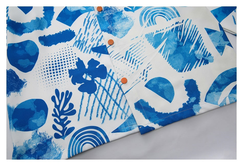 Close-up of a white shirt with an abstract blue print and orange buttons along the placket.