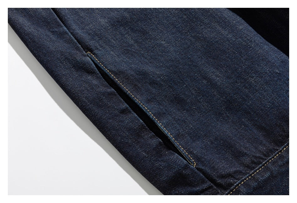 Close-up of a dark indigo denim jacket seam and panel with golden stitching.