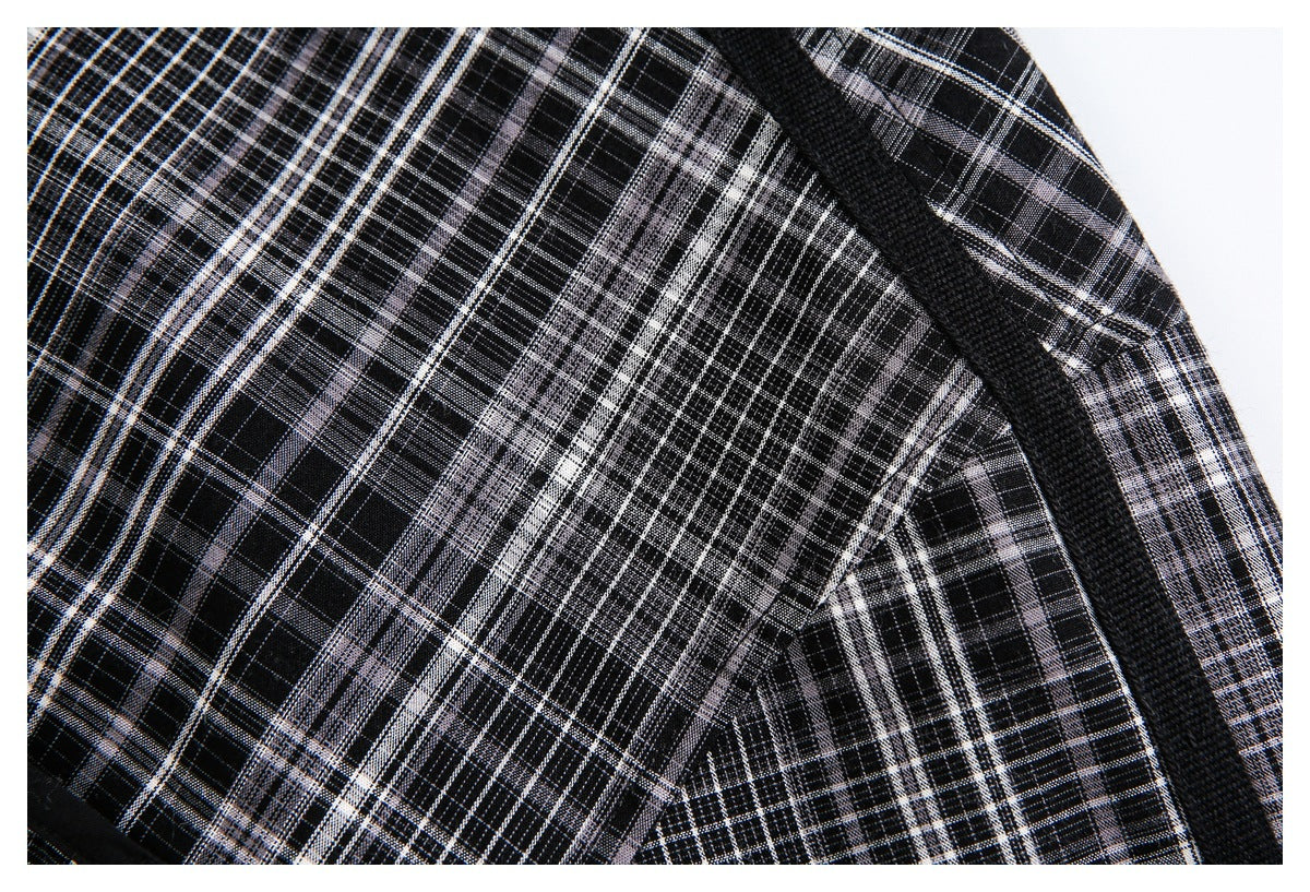 Close-up of black, gray, and white plaid fabric with a wide black trim seam.