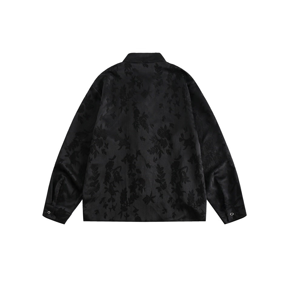 Back view of a black long-sleeved shirt with a stand collar, button cuffs, and a subtle floral pattern.