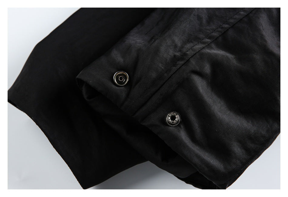 Close-up of a black garment with two round metal snap fasteners along a folded edge.