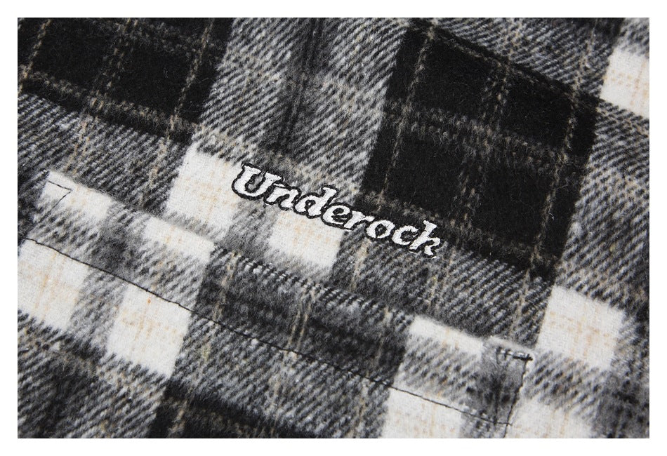 Close-up of embroidered lettering on black, gray, and cream plaid fabric.