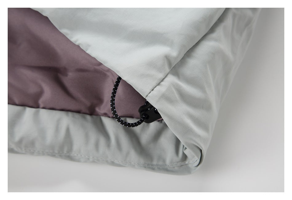 Close-up of a light gray garment hem with a black cord loop and toggle.