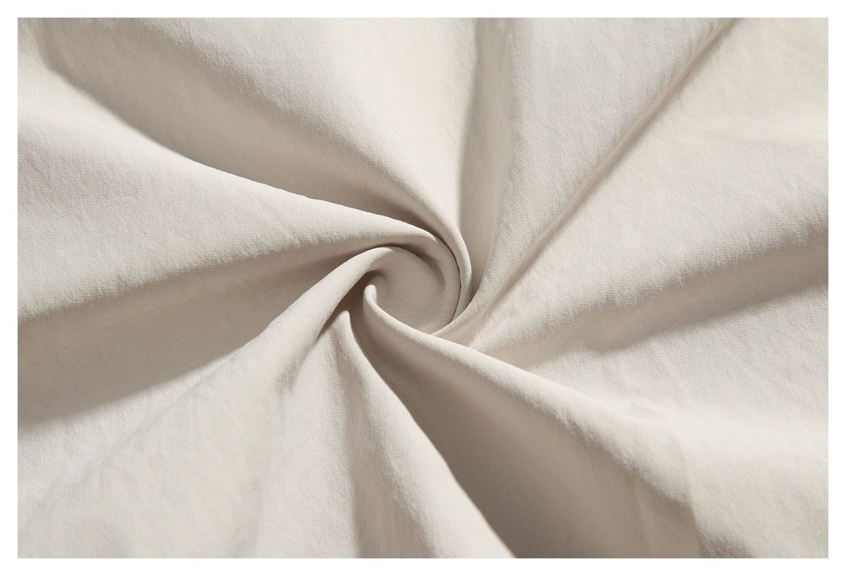 Close-up of light beige fabric gathered into a swirl, showing its woven surface.