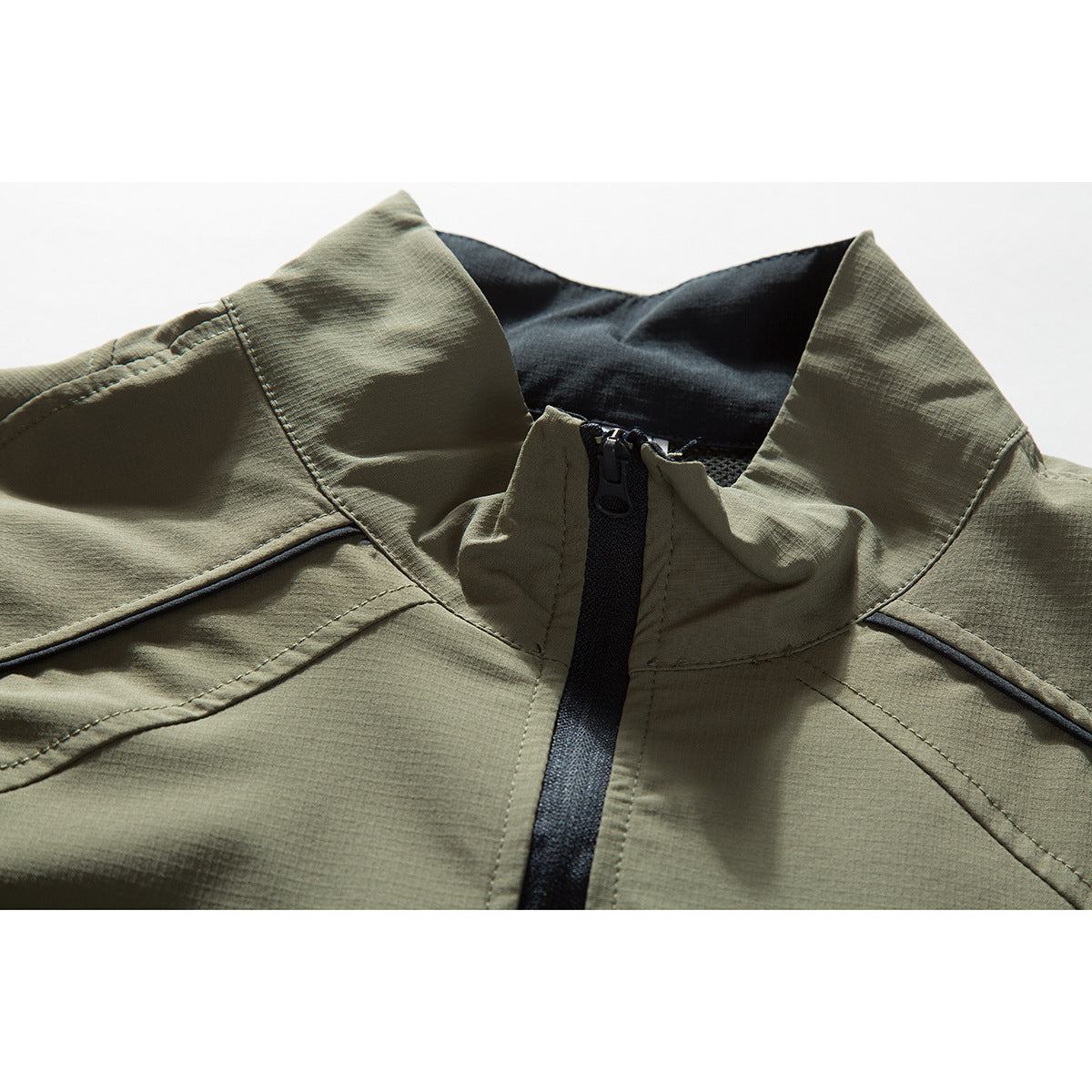 Close-up of an olive-gray jacket collar and short black zipper with dark lining.