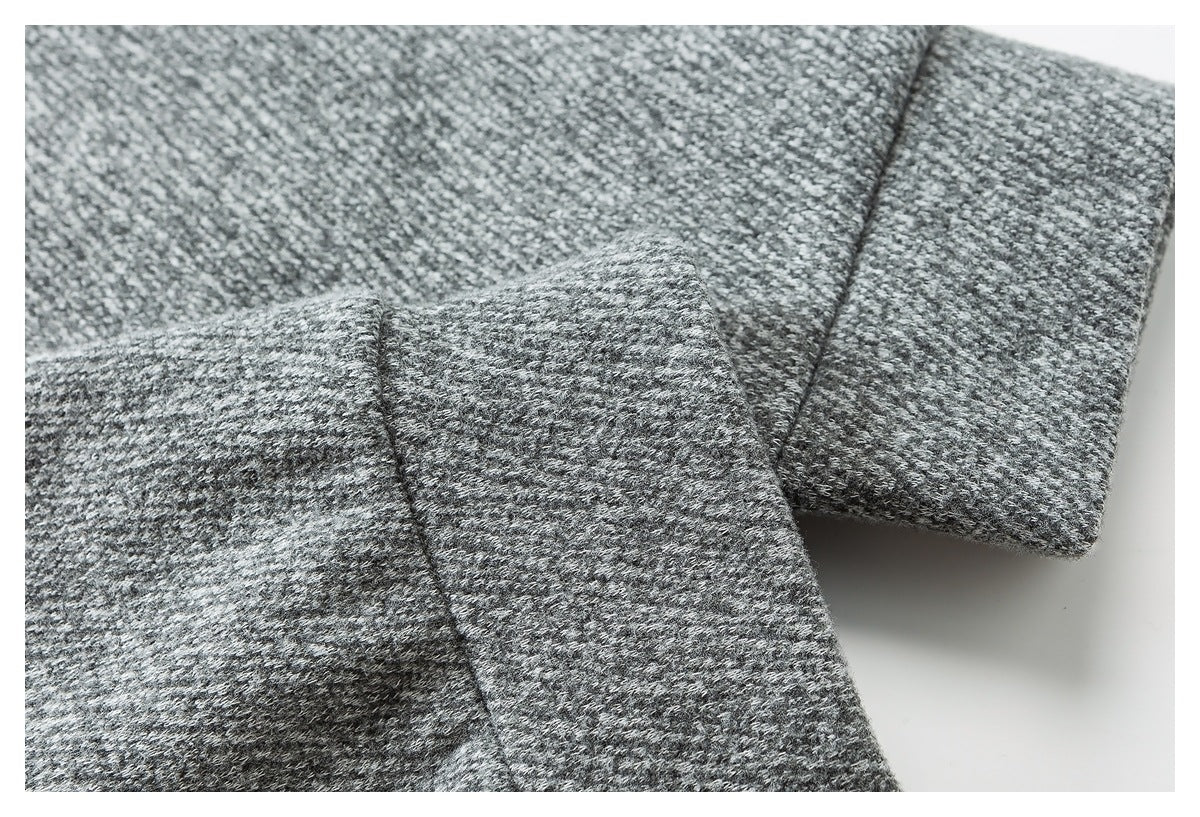 Close-up of a folded edge and stitched seam on gray textured garment fabric.