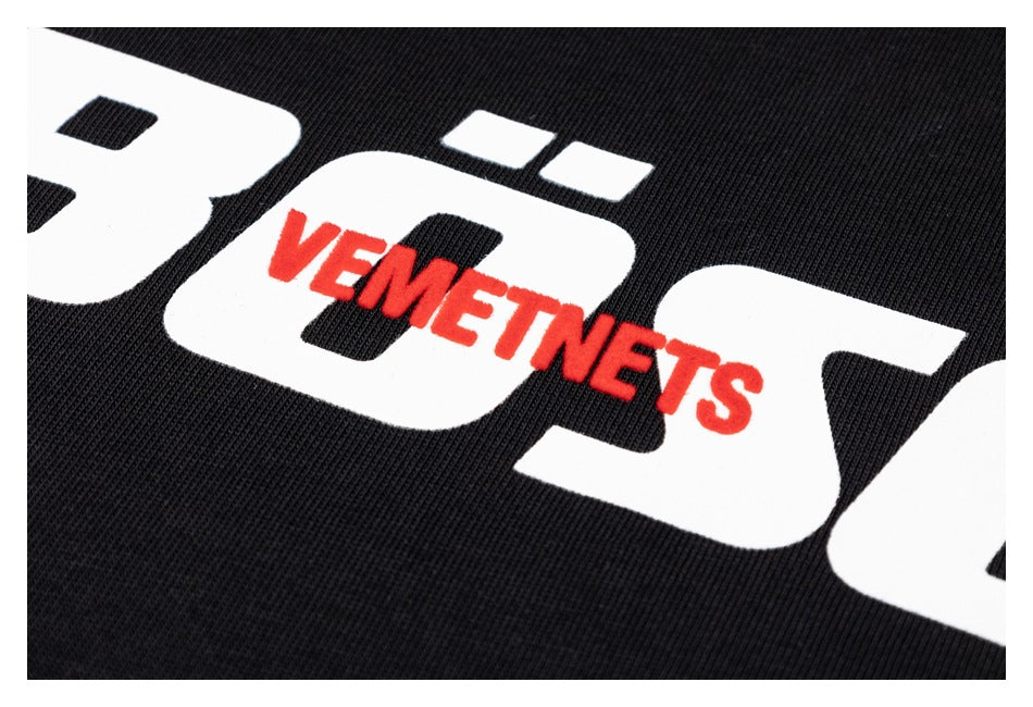 Close-up of a black ribbed garment with large white lettering and a raised red word graphic.