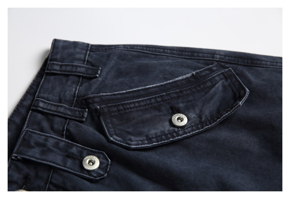Close-up of a dark charcoal jeans flap pocket with metal-button closure and waistband tabs.