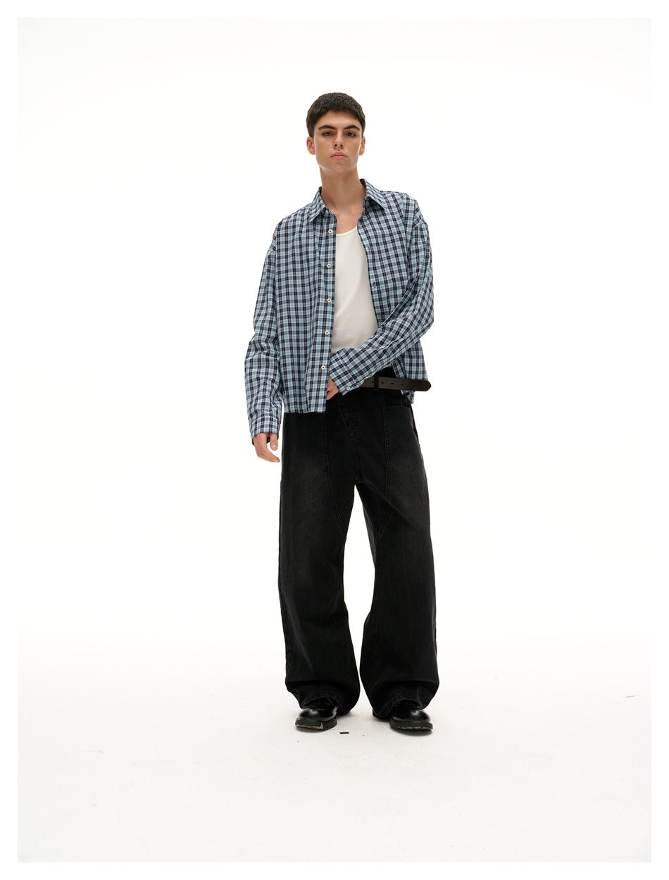 Front view of a model wearing an open blue, gray, and black plaid shirt over a white tank with wide black trousers.