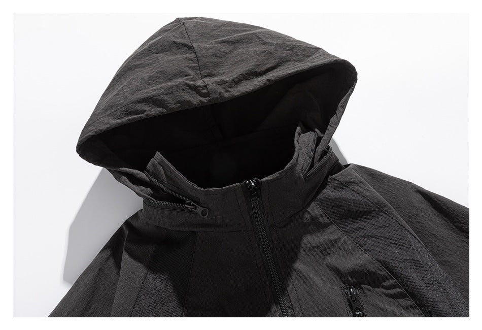 Close-up of the black jacket's large hood, high zip collar and upper front with zippered pockets.
