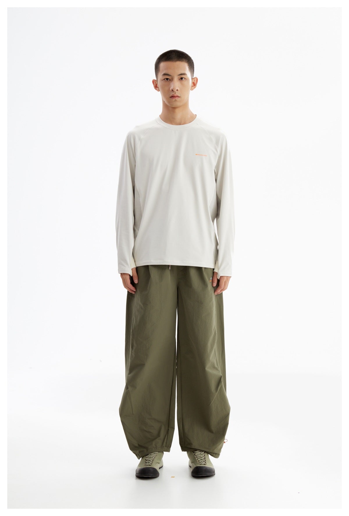 Model wearing an off-white long-sleeve shirt with olive wide-leg trousers, shown from the front.