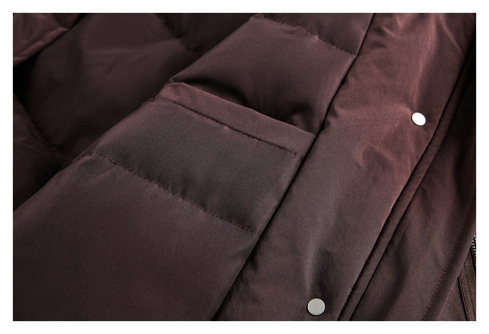 Close-up of a dark burgundy padded coat with stitched panels and silver snap fasteners.