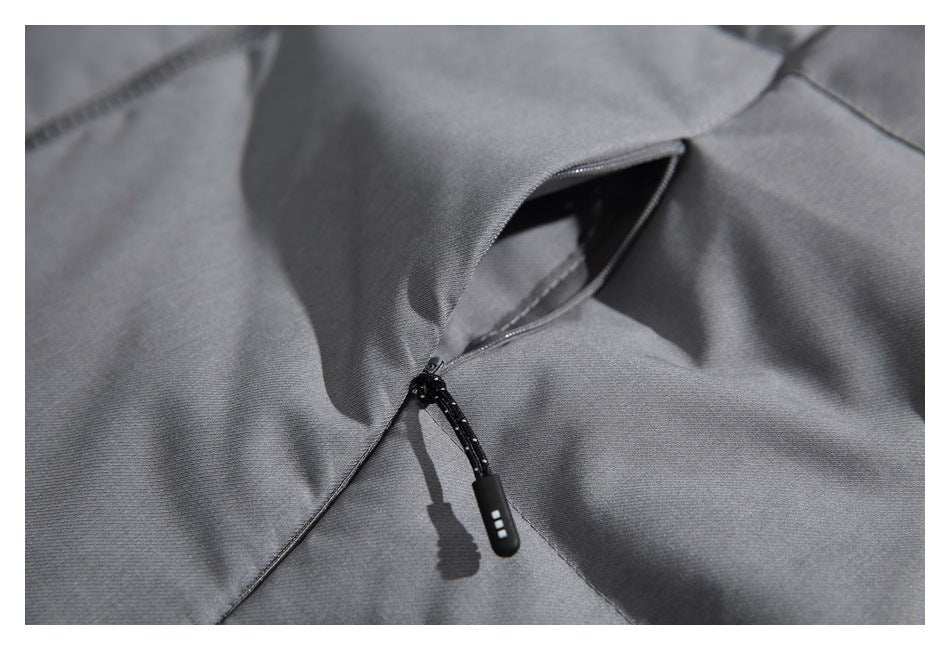 Close-up of a dark gray jacket zipper pocket with a black cord pull.