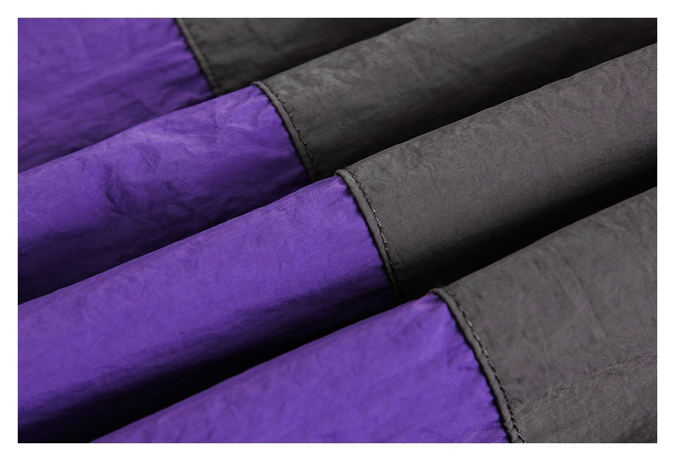 Close-up of layered purple and charcoal gray fabric sections with stitched edges.