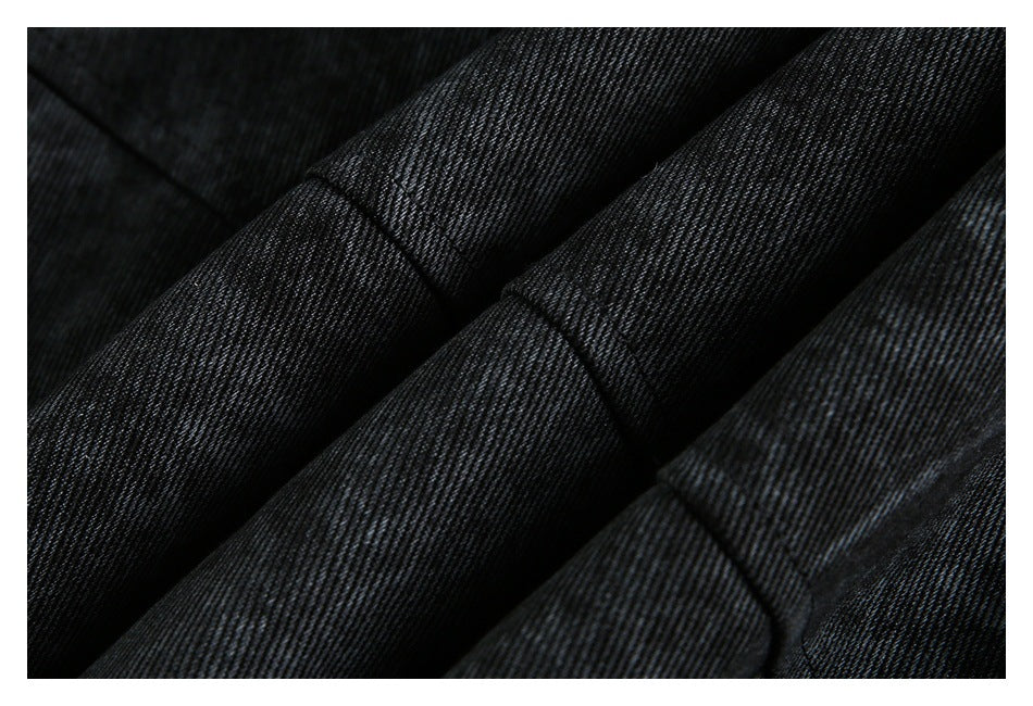 Close-up of dark jacket fabric folded to show parallel stitched seams and its fine texture.