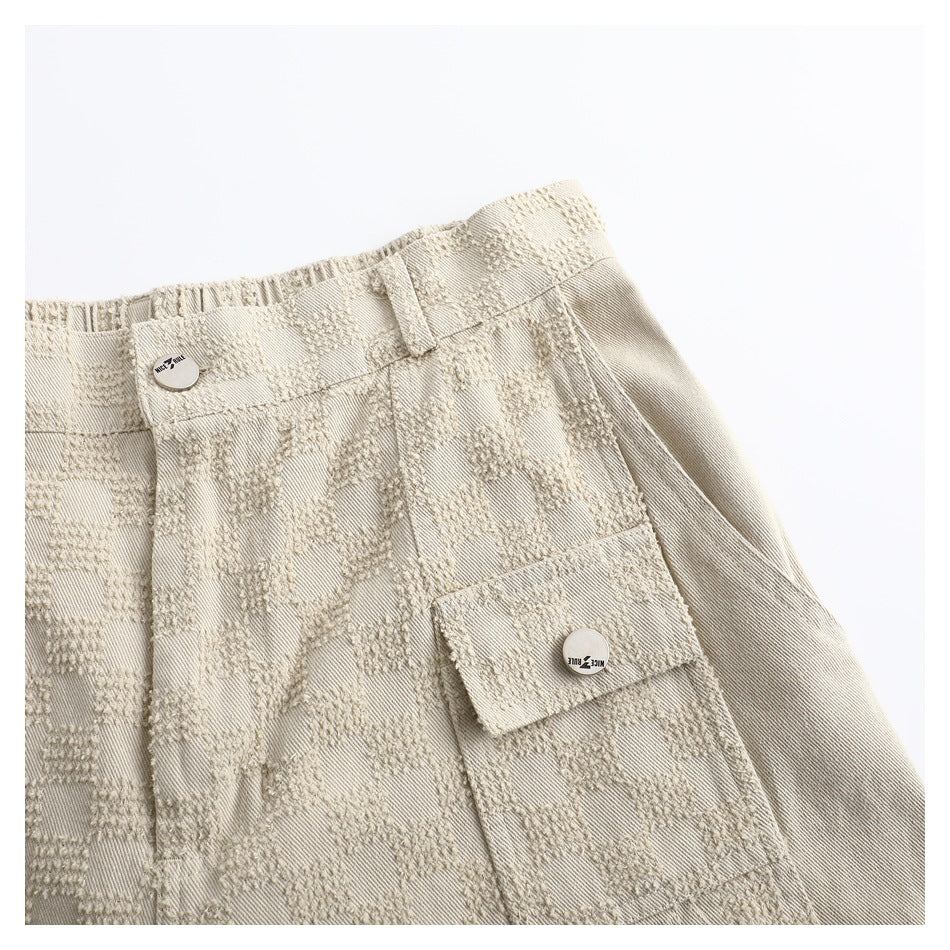 Close-up of the beige textured trousers' waistband, belt loop and front flap cargo pocket.