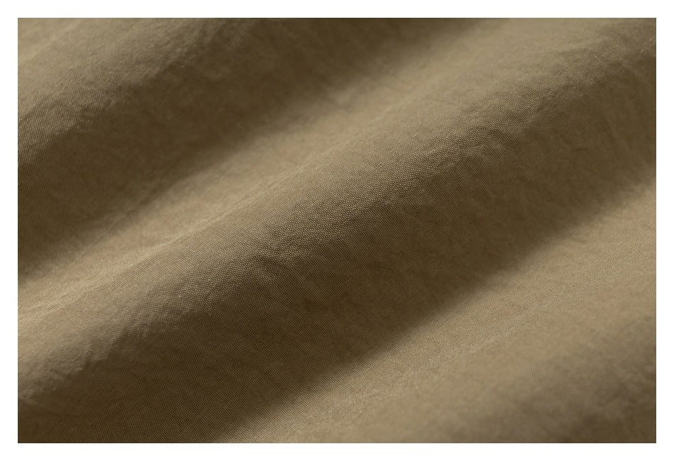 Close-up of tan-brown fabric with a fine, tightly woven texture and soft folds.