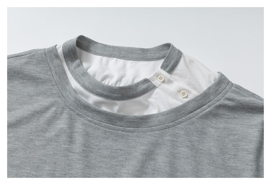 Close-up of a gray T-shirt neckline with a white inset collar and two small buttons.