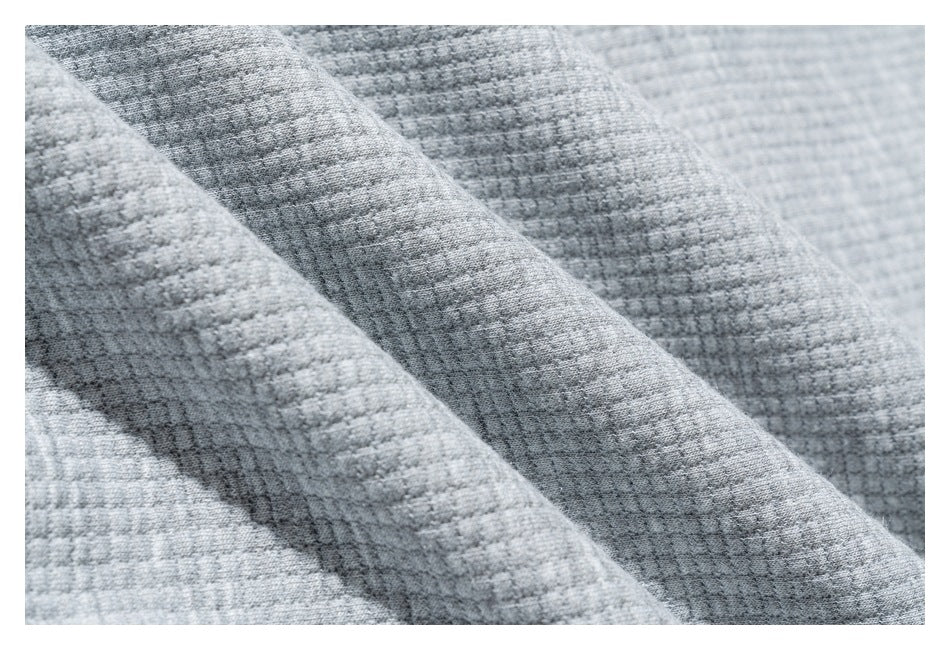 Macro view of the light gray garment's raised, grid-like knit texture.