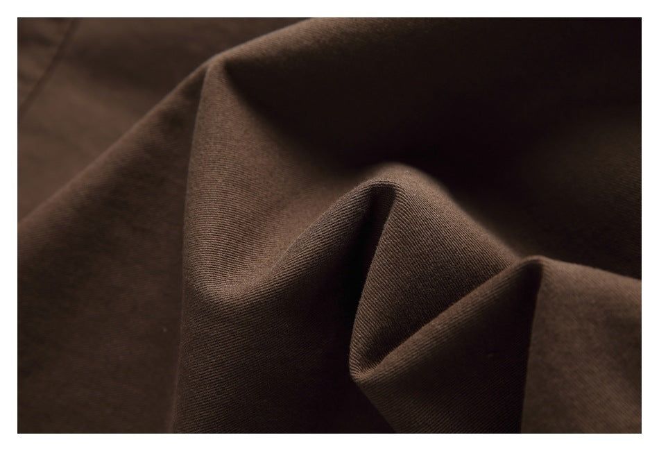 Close-up of dark brown fabric draped into soft folds, showing its fine textured surface.