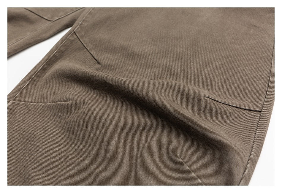 Close-up of taupe trouser fabric and stitching, with part of a leg seam visible.