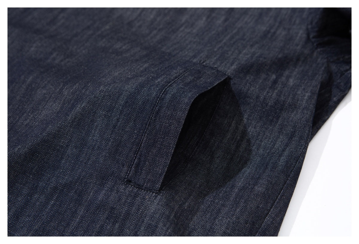 Close-up of a slanted welt pocket on dark indigo garment fabric.