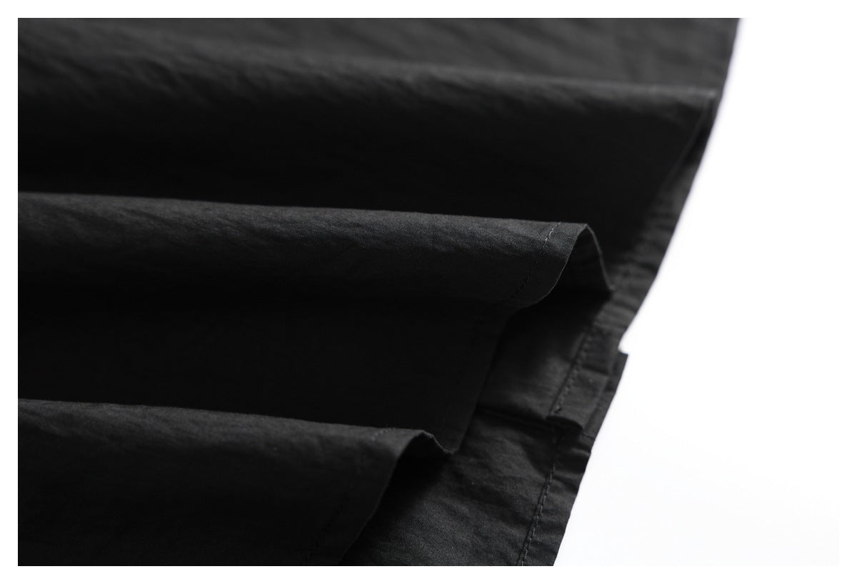 Close-up of folded black fabric showing a stitched hem and layered edges.