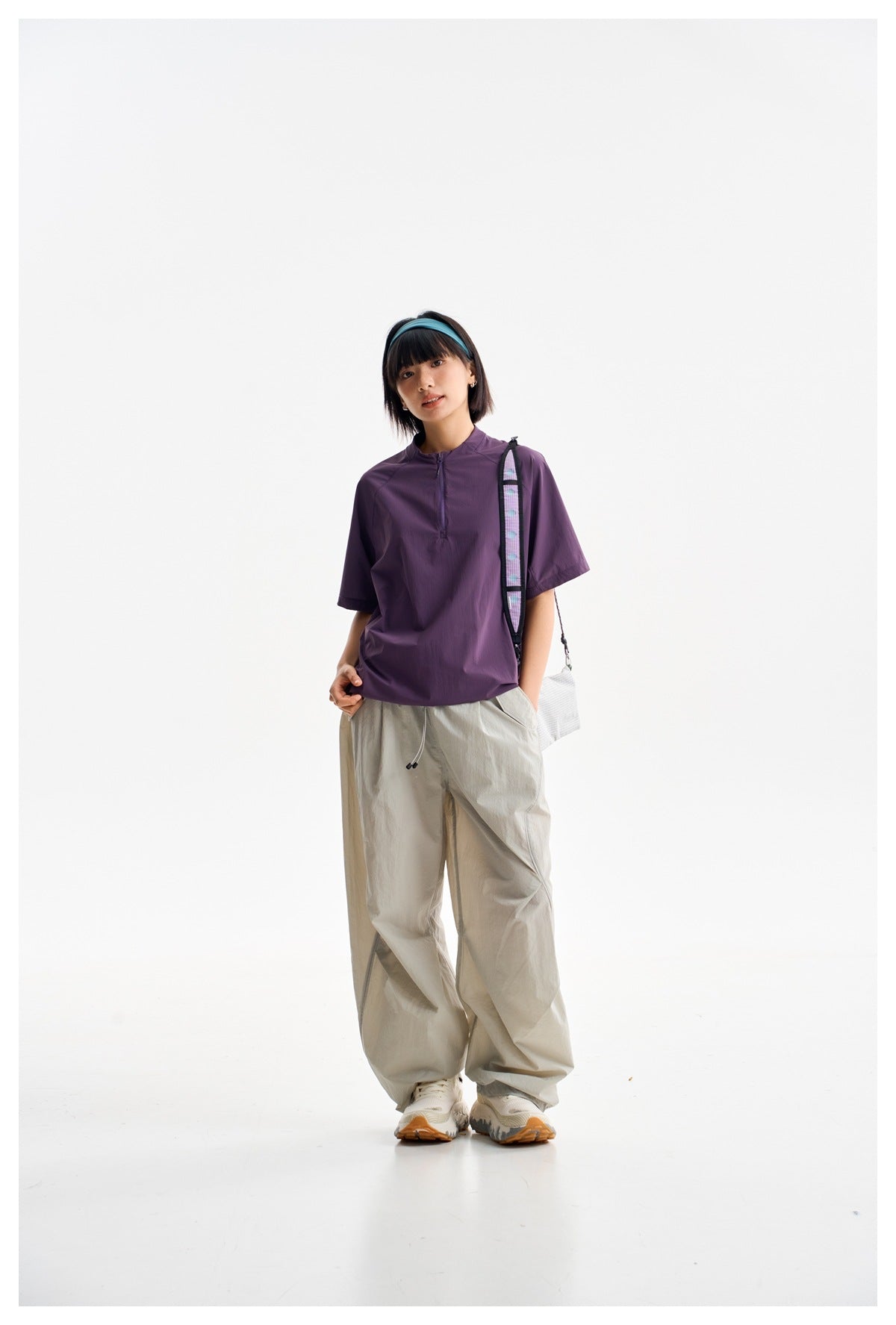 Model wearing a plum short-sleeve pullover with a short zip neckline and loose light-gray pants.