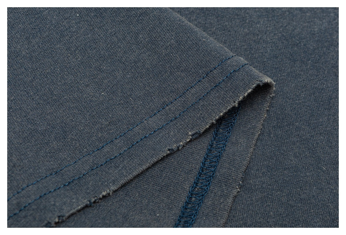 Close-up of a blue-gray shirt hem with double stitching and an overlocked seam.
