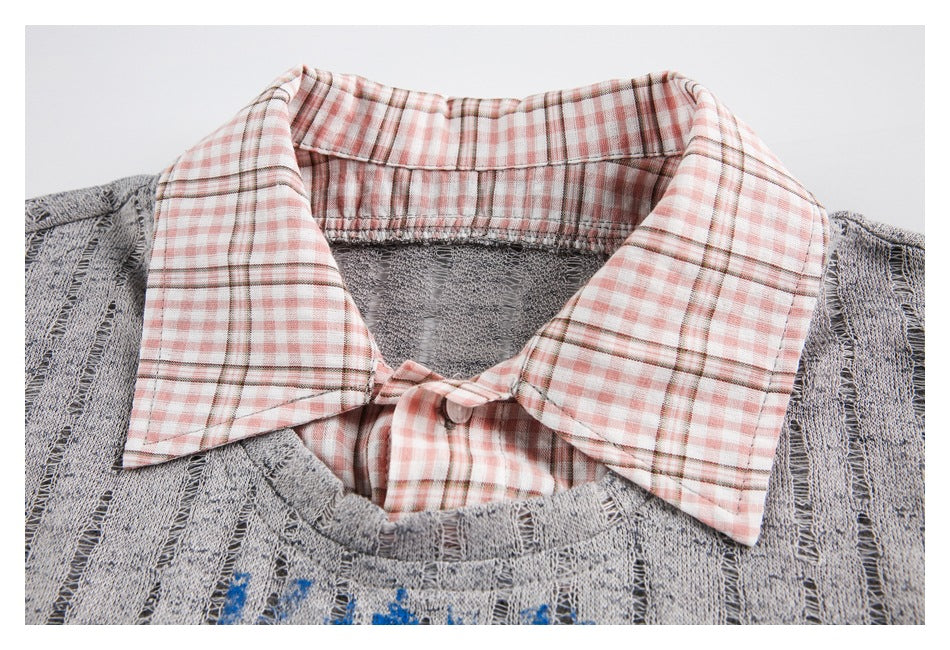 Close-up of a gray open-knit sweater with a pink-and-white plaid shirt collar layered underneath.