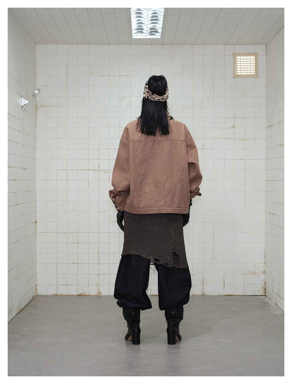 Back view of a model wearing an oversized brown jacket with curved seam detailing.
