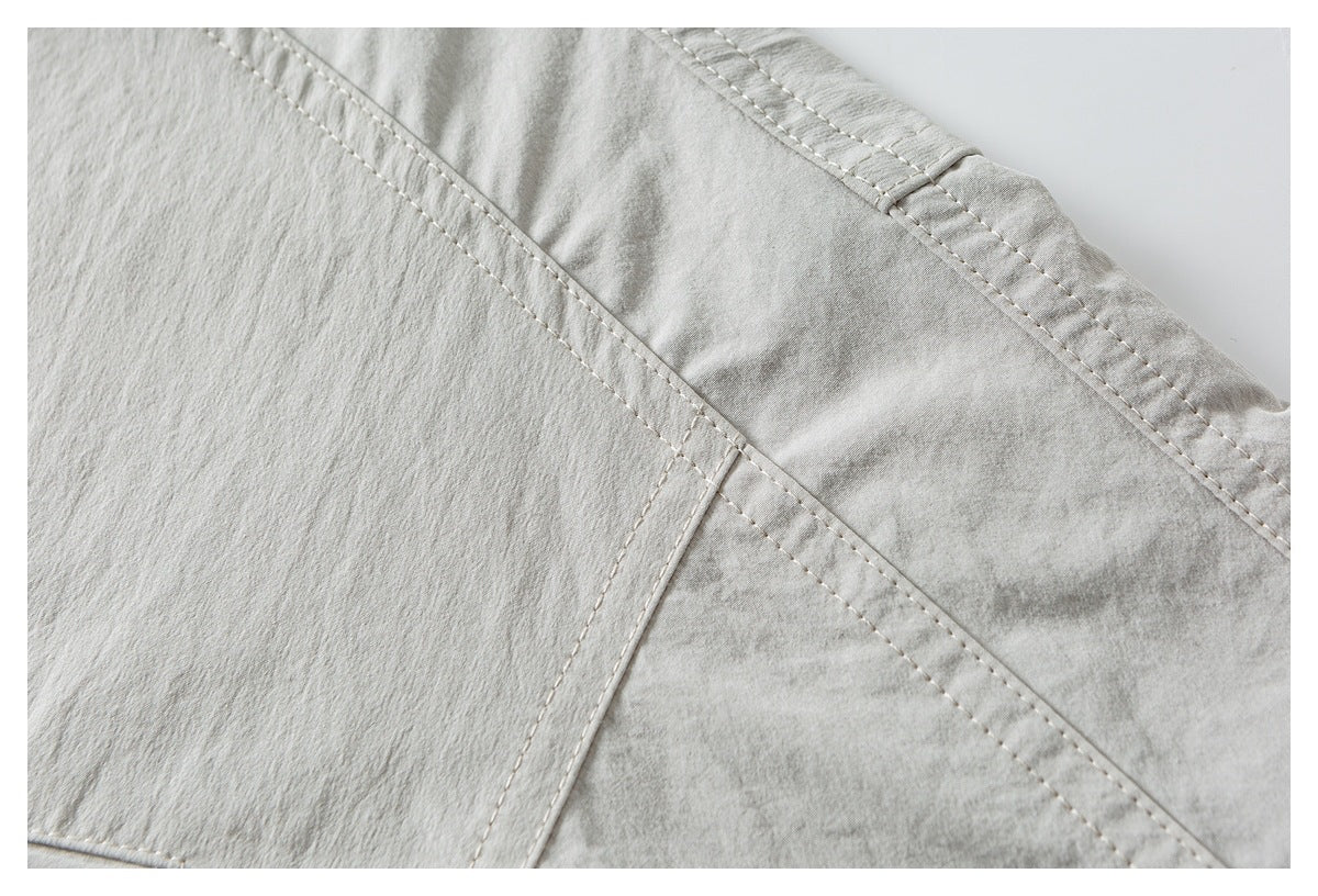 Close-up of intersecting stitched seams on light gray-beige fabric.