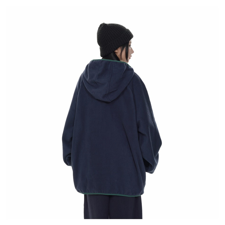 Rear view of a model wearing an oversized navy hooded jacket with green trim.