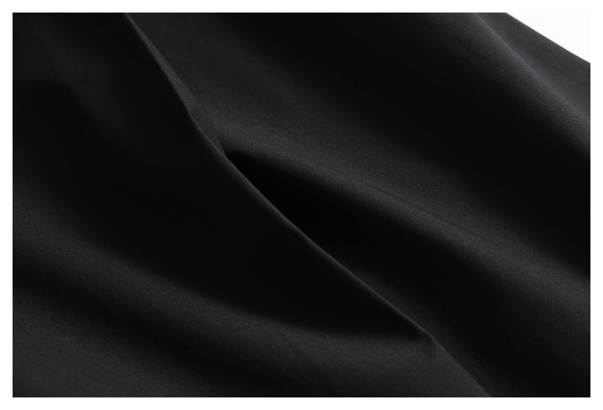 Close-up of smooth black trouser fabric arranged in soft folds.