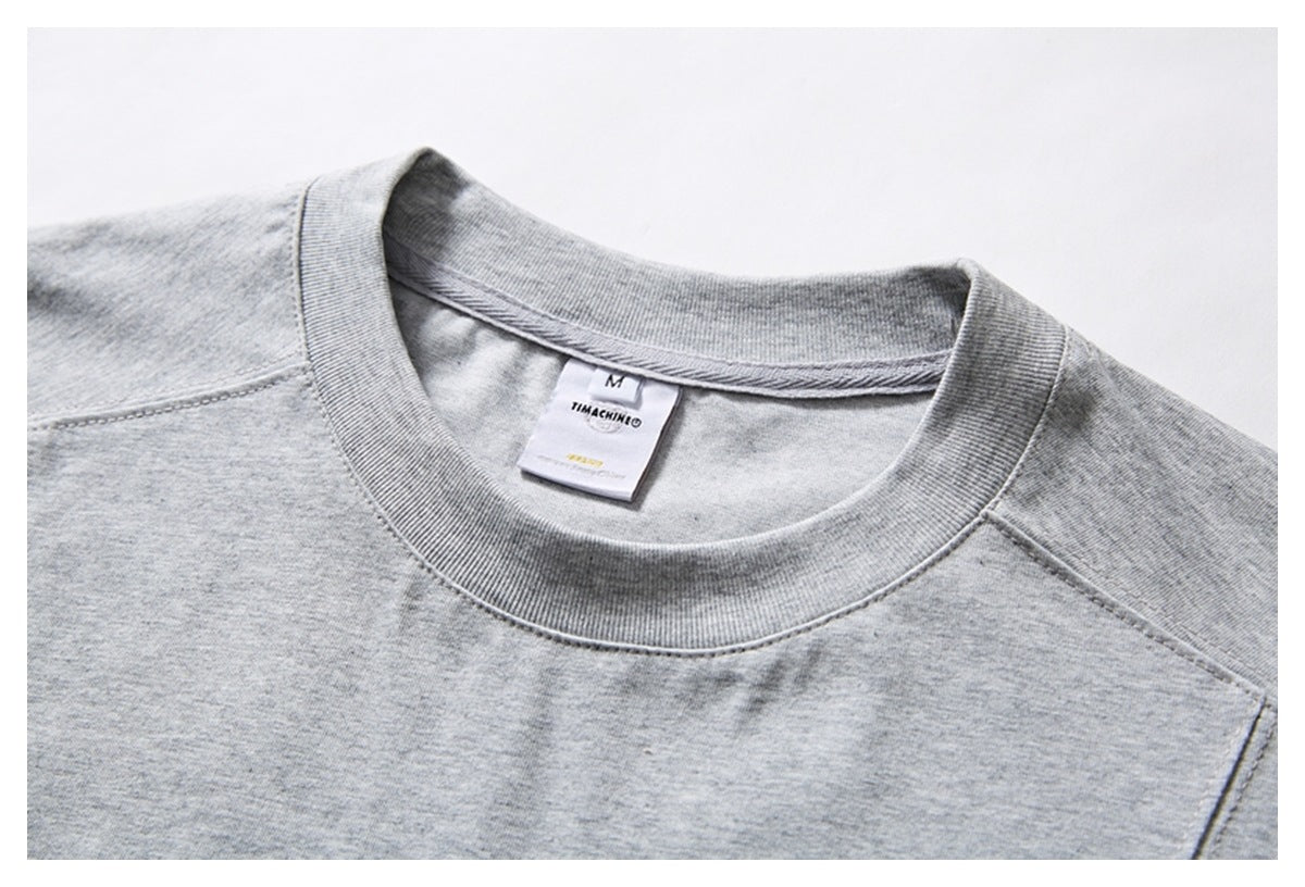 Close-up of a light gray T-shirt’s ribbed crew neck, shoulder seams, and inner label.