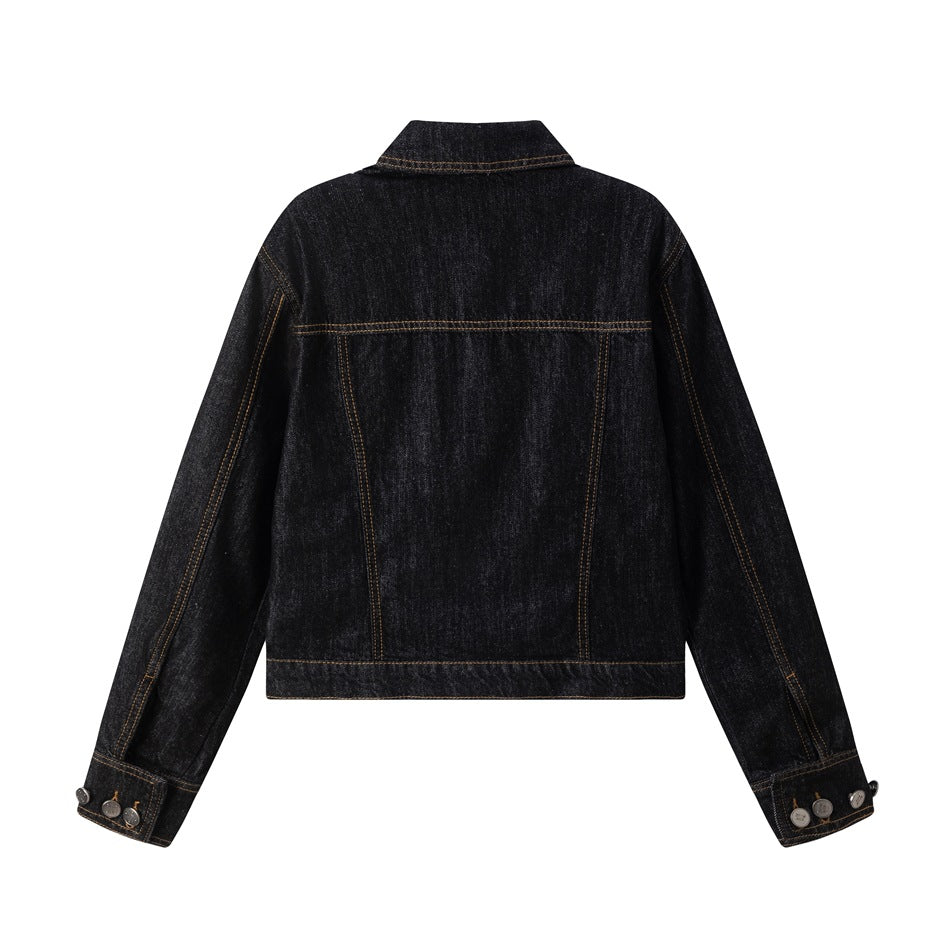 Back view of a dark indigo denim jacket with contrast stitching, a yoke seam, and buttoned cuffs, shown flat.
