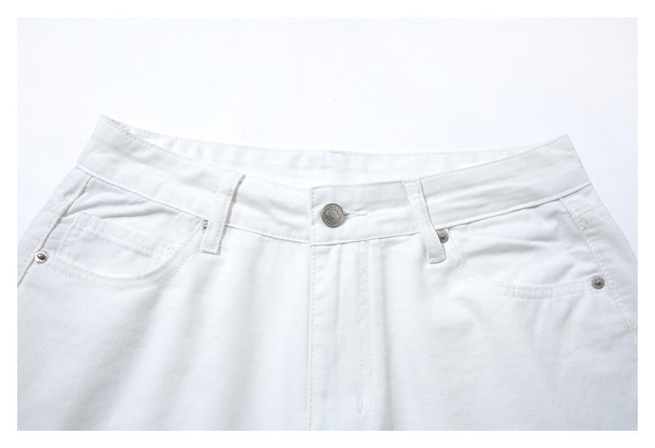 Close-up of the front waistband and pockets of white pants, with a metal button and rivets.