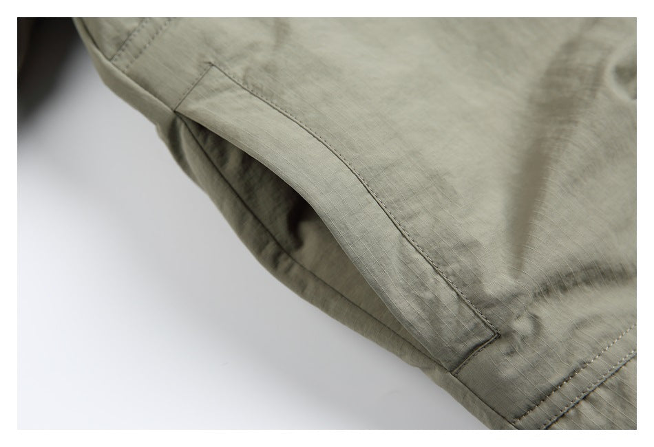 Close-up of a sage-gray shirt seam and reinforced fabric panel.