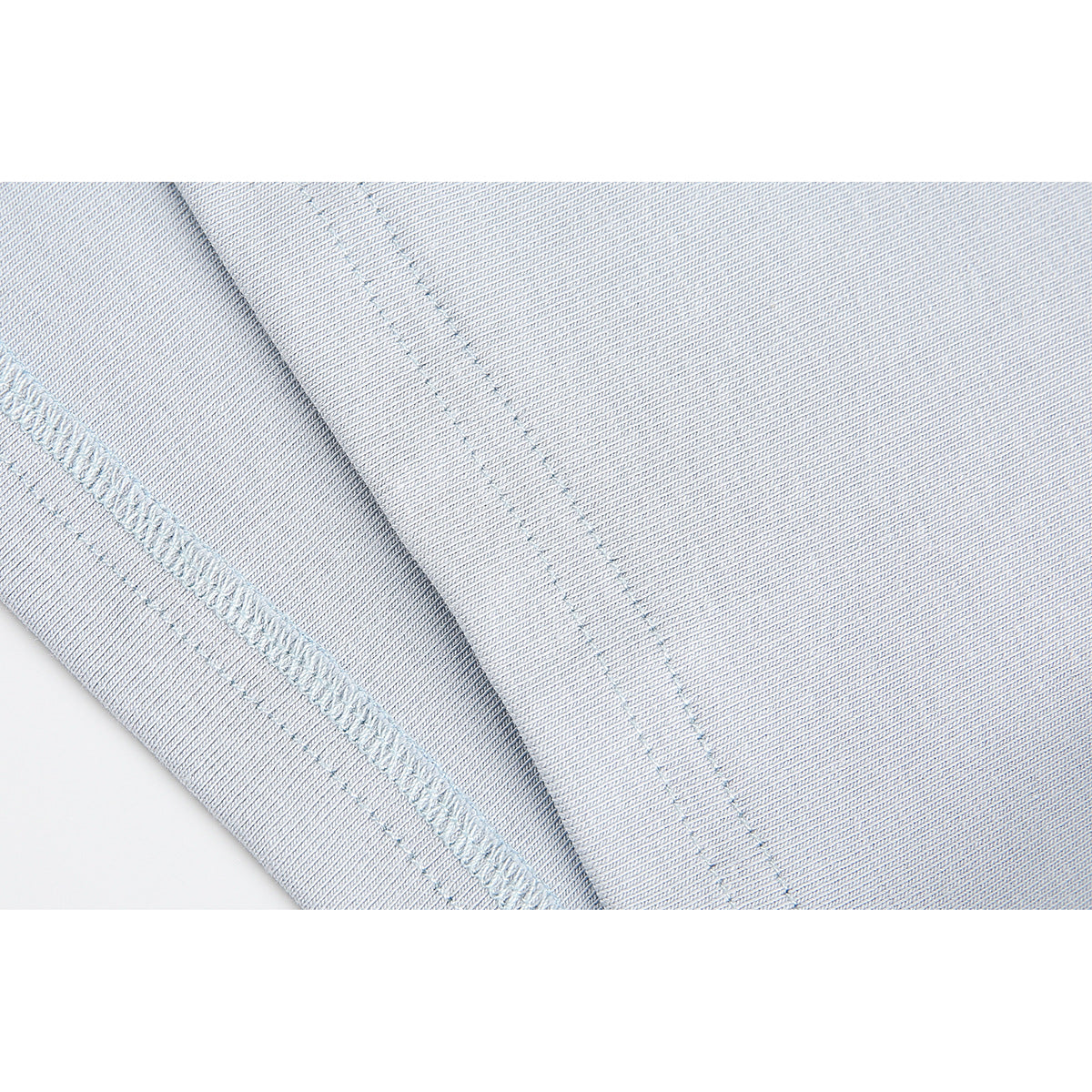 Close-up of pale blue fabric showing a stitched seam and overlocked edge.