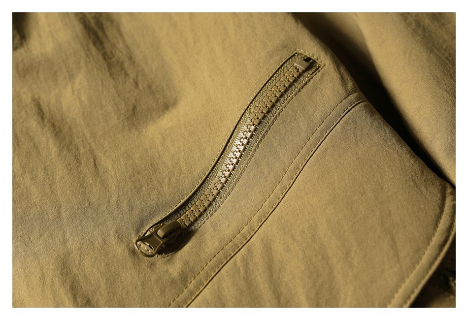 Close-up of a tan olive jacket showing a diagonal zipper and stitched seam.